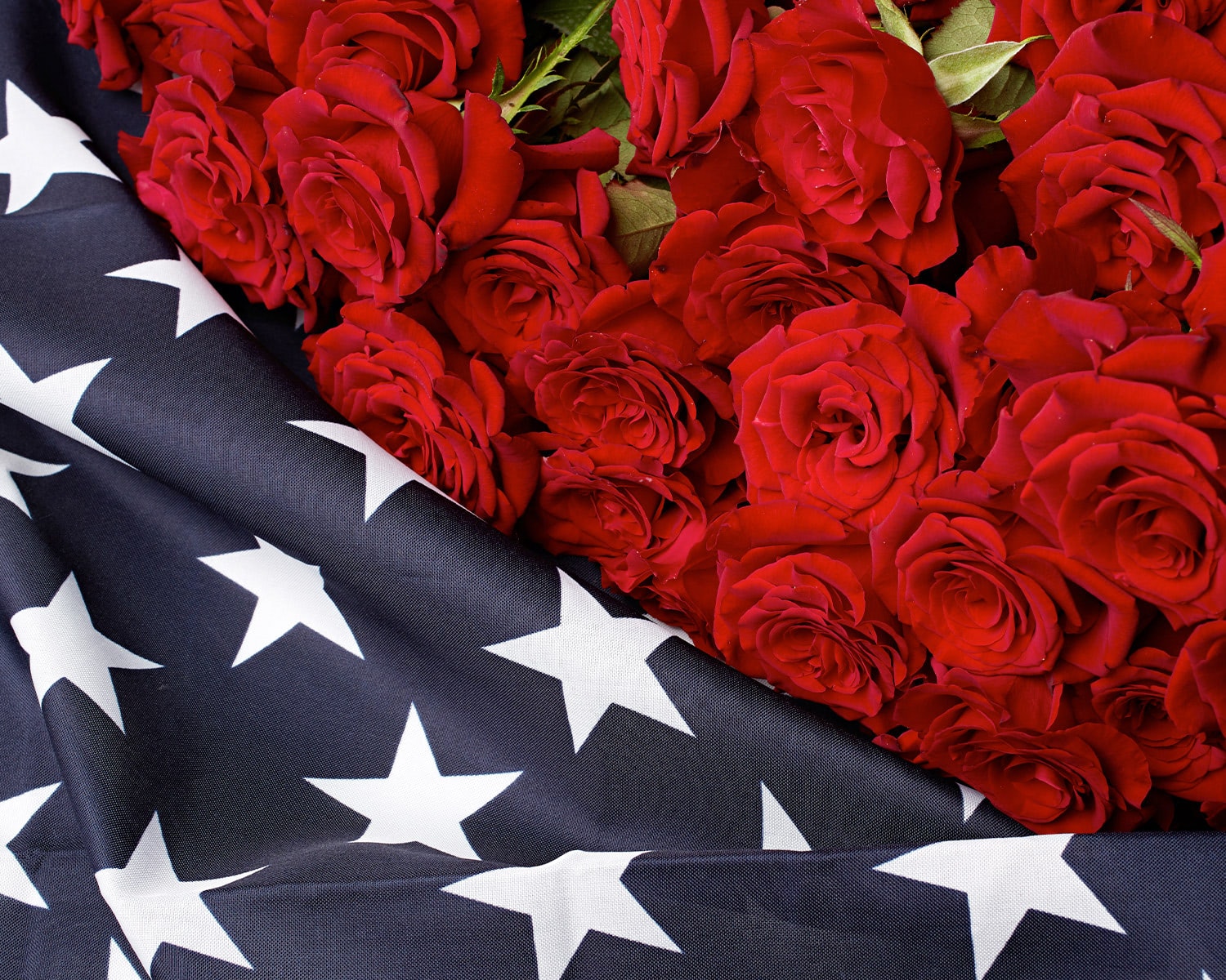 Red rose arrangement draped with American flag fabric for patriotic Fourth of July floral d&eacute;cor