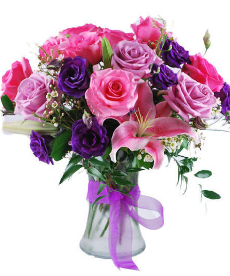 Pink, lavender and purple flowers in a glass vase tied with purple ribbon.