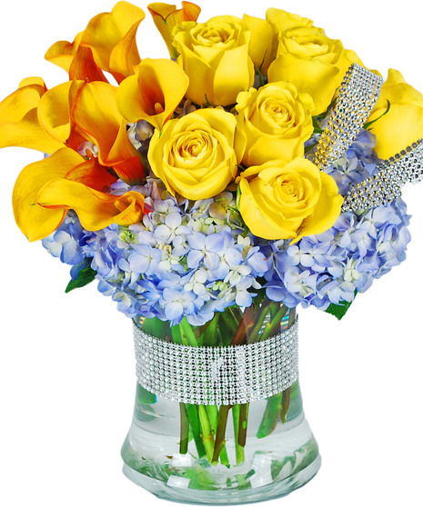 Sunset callas, yellow roses and blue hydrangea in a clear glass vase with a touch of bling.