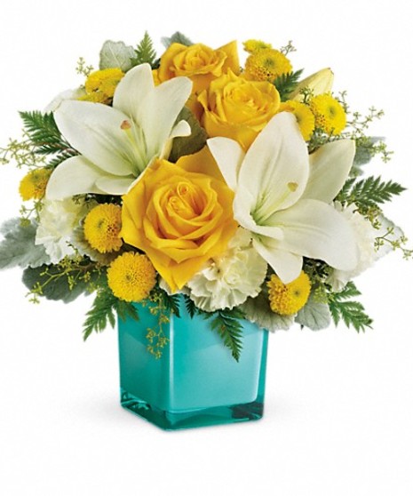 Golden roses and white lilies in an aqua cube vase.