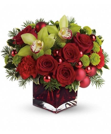 Red cube vase of green and red flowers accented with ornament balls. 
