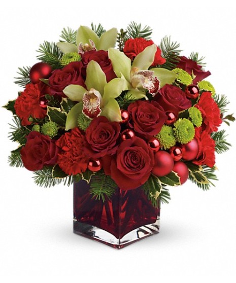 Red cube vase of green and red flowers accented with ornament balls. 