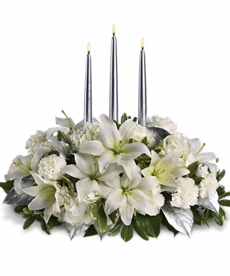 Winter centerpiece of white hydrangea, roses, asiatic lilies, carnations and greenery with three silver taper candles.