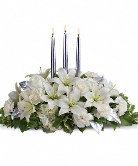 Winter centerpiece of white hydrangea, roses, asiatic lilies, carnations and greenery with three silver taper candles.