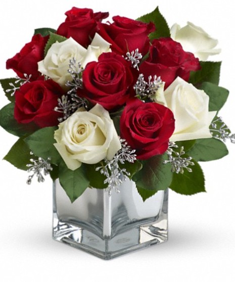 Red and white roses in a mirrored cube vase.