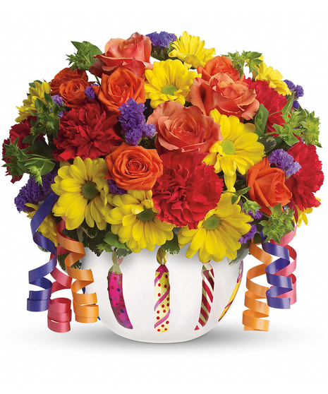 Bright flowers in a frosted glass bowl vase adorned with a shiny birthday candle motif.