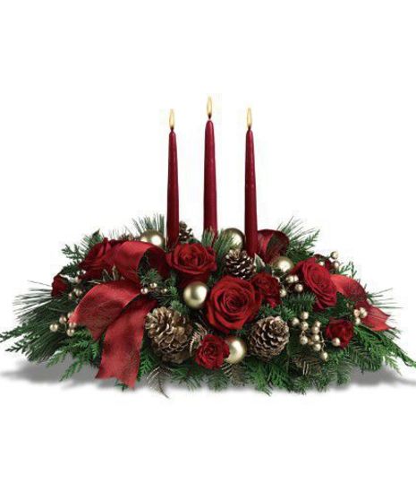 Christmas centerpiece of red flowers, greenery, pine cones, ornaments, ribbon and candles.