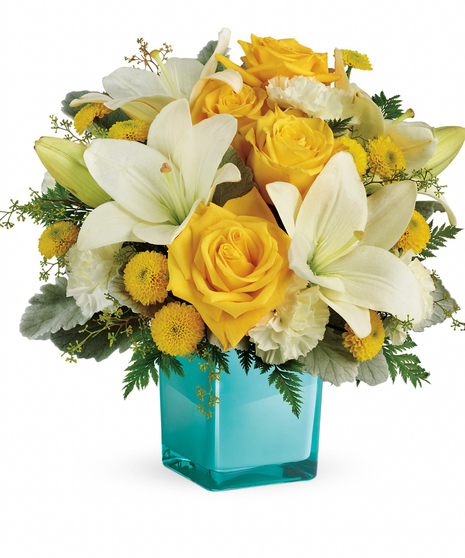 Golden roses and white lilies in an aqua cube vase.