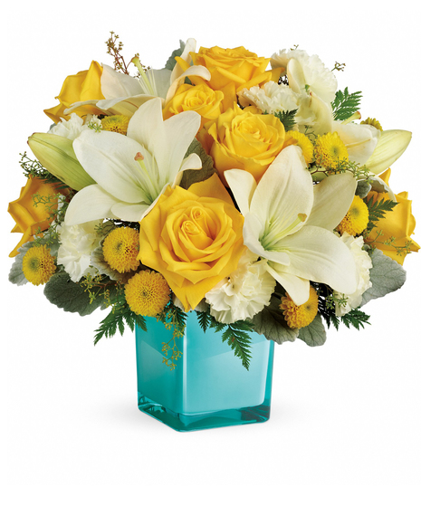 Golden roses and white lilies in an aqua cube vase.