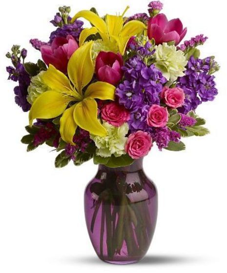 Colorful yellow, raspberry, purple and green flowers in a purple glass vase.
