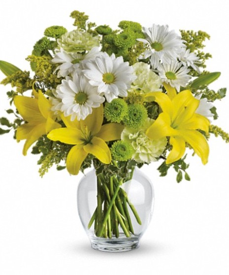 Yellow and green flowers in a glass vase.