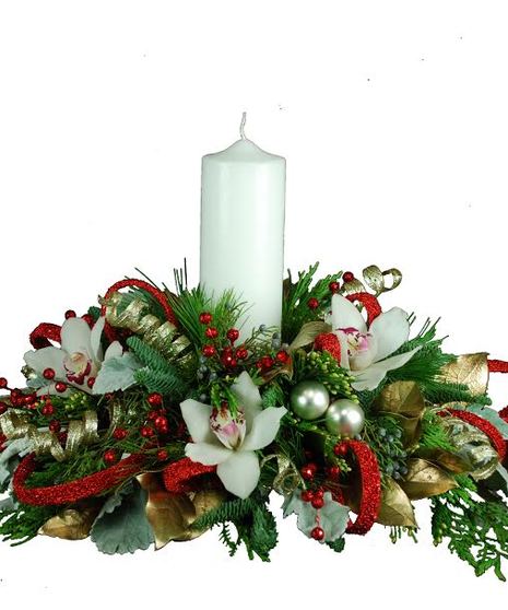 Holiday centerpiece of orchids, greenery, ornaments and a white pillar candle. 